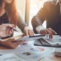 Image of two peoples arms pointing at a tablet