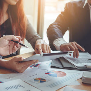 Image of two peoples arms pointing at a tablet