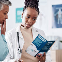 Image og black doctor holding a brochure showing someone information
