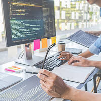 two hands on a desk in front of a computer with code on it