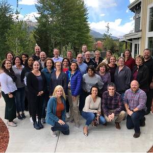a crowd of people, huddled together, smiling for a work photo