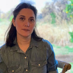 Photo of woman with brown hair in a gray shirt staring at the camera